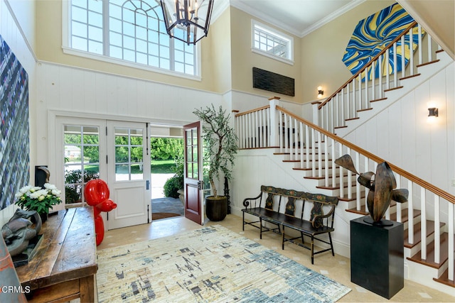 entryway with a towering ceiling, plenty of natural light, and crown molding