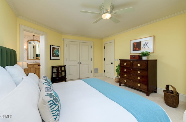 carpeted bedroom with ceiling fan, a closet, ensuite bath, and ornamental molding