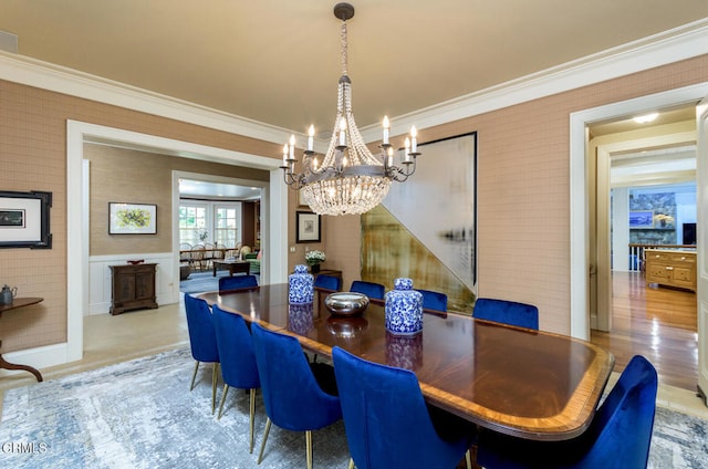 dining space with light hardwood / wood-style flooring, a notable chandelier, and crown molding