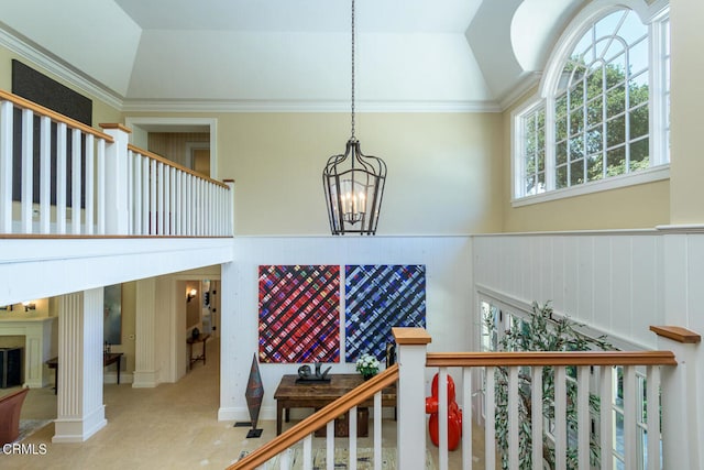 stairs featuring carpet flooring, a notable chandelier, lofted ceiling, a fireplace, and ornamental molding