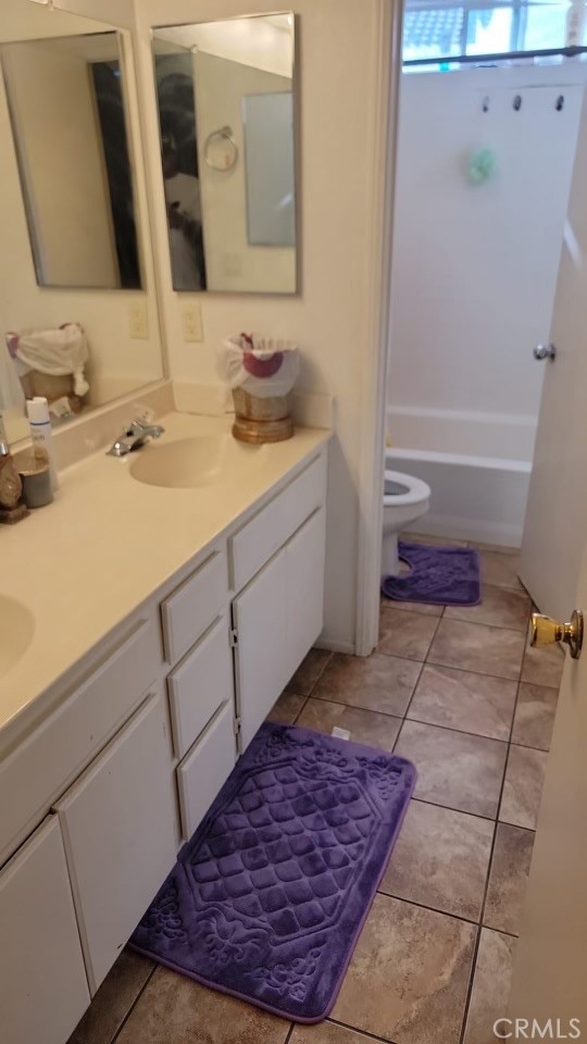 bathroom with vanity, tile patterned floors, toilet, and a tub