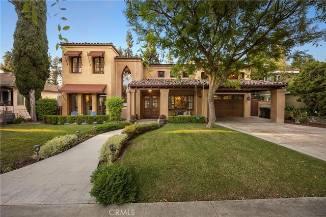 mediterranean / spanish home with a garage and a front lawn