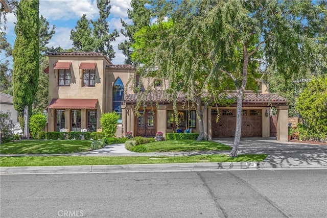 mediterranean / spanish-style home featuring a garage and a front yard