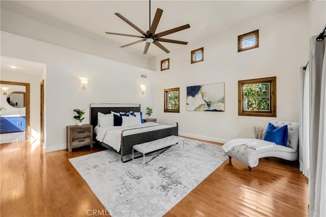 bedroom featuring ceiling fan, hardwood / wood-style floors, and a towering ceiling