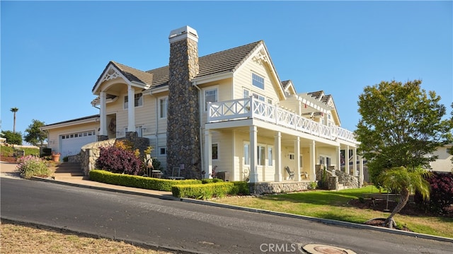 view of front of property with a balcony, a porch, a garage, and a front lawn