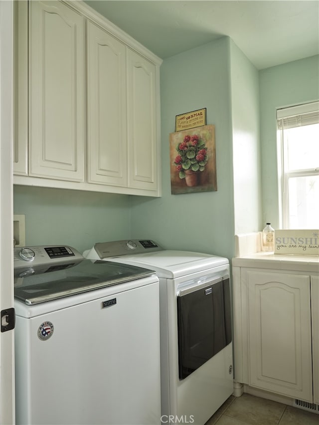 laundry room featuring washer and clothes dryer, cabinets, and light tile patterned floors