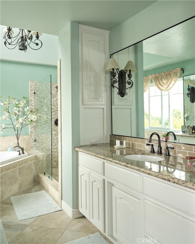 bathroom with shower with separate bathtub, a chandelier, vanity, and tile patterned floors