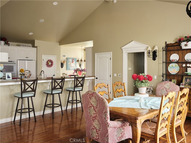 dining room featuring an inviting chandelier, dark hardwood / wood-style floors, sink, and high vaulted ceiling