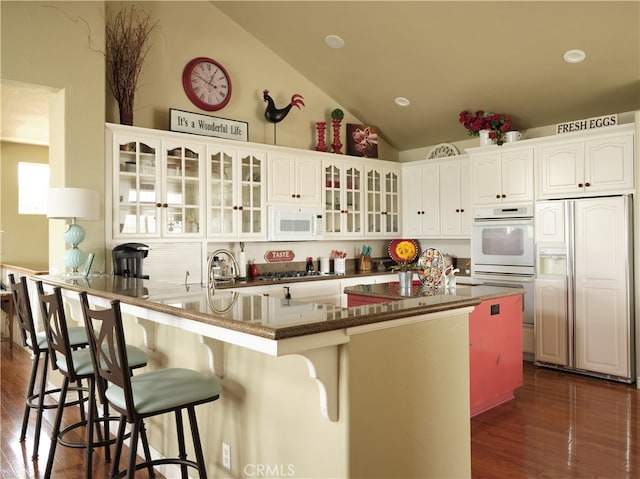 kitchen featuring white cabinets, dark hardwood / wood-style floors, a kitchen bar, and white appliances