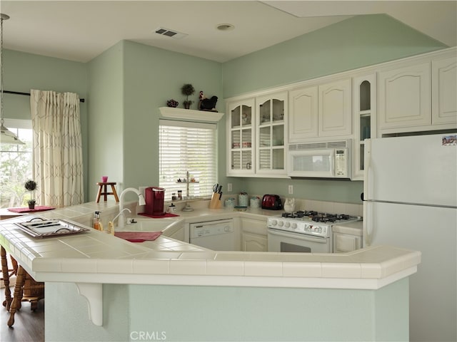 kitchen featuring white cabinets, kitchen peninsula, white appliances, and a wealth of natural light