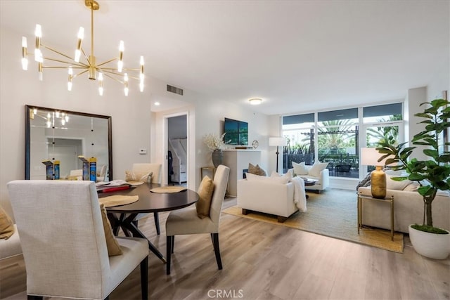 dining room featuring an inviting chandelier, a wall of windows, and hardwood / wood-style floors