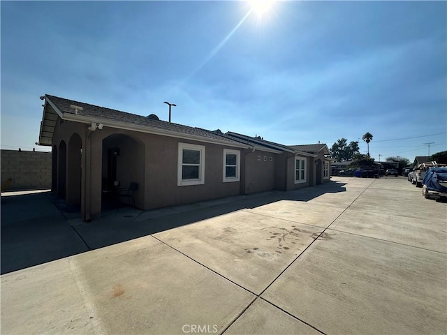 10693 Valencia St, Bloomington, CA 92316 - view of side of home featuring stucco siding, fence, and a patio