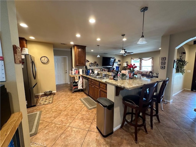 10693 Valencia St, Bloomington, CA 92316 - kitchen featuring appliances with stainless steel finishes, a peninsula, arched walkways, a breakfast bar area, and a sink
