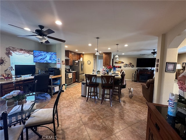 dining space with a fireplace, ceiling fan, and tile patterned floors