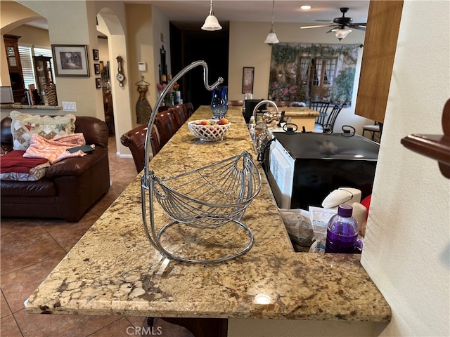 kitchen with light stone countertops, ceiling fan, and tile patterned floors