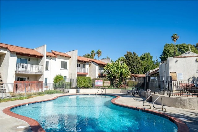 pool with a residential view, a patio, and fence