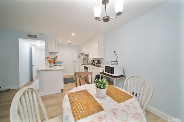 dining area featuring light wood-type flooring, baseboards, visible vents, and an inviting chandelier