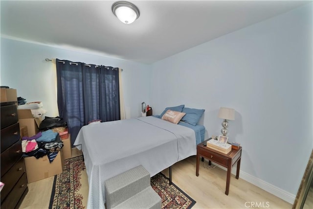 bedroom featuring light wood finished floors and baseboards