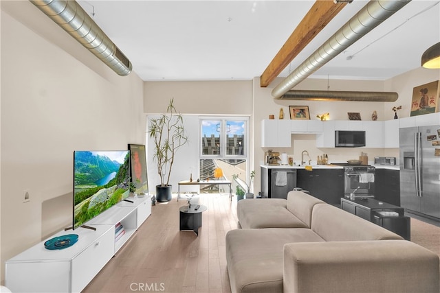 living room featuring a high ceiling, beam ceiling, hardwood / wood-style flooring, and sink