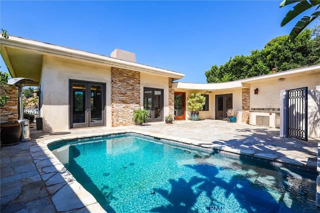 view of pool featuring exterior kitchen, french doors, and a patio area