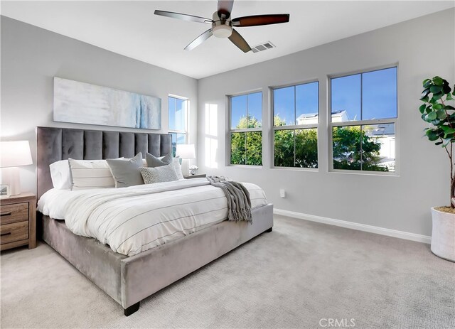 carpeted bedroom featuring multiple windows and ceiling fan