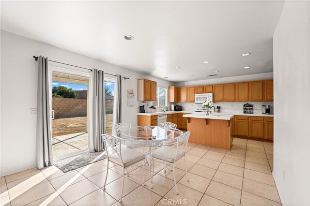 kitchen with a healthy amount of sunlight, white appliances, a kitchen bar, and an island with sink