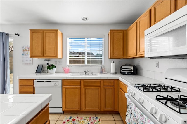 kitchen featuring white appliances, tile countertops, light tile patterned flooring, and sink