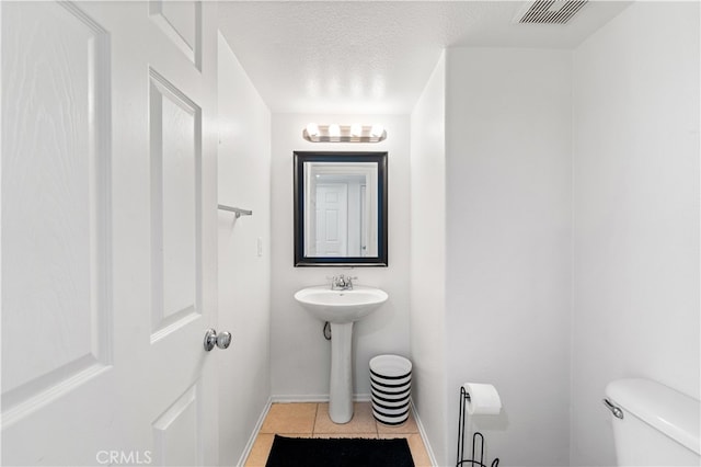 bathroom featuring tile patterned flooring, a textured ceiling, and toilet