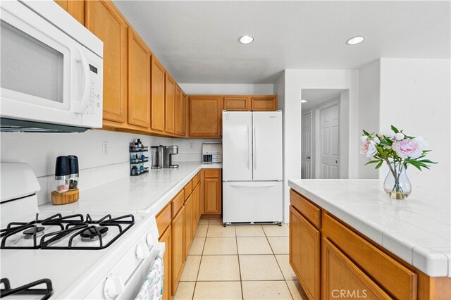 kitchen with tile counters, white appliances, and light tile patterned flooring