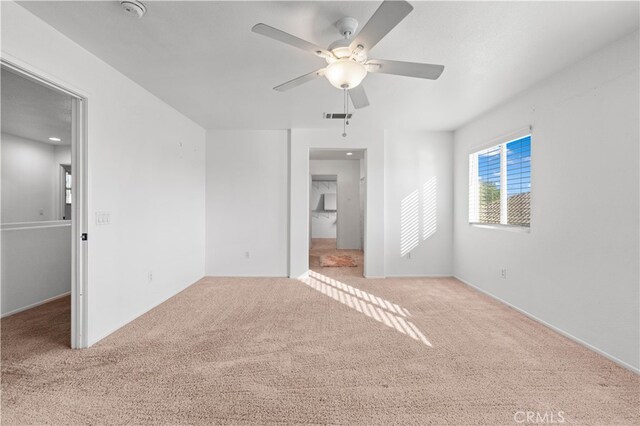 unfurnished bedroom featuring ceiling fan, light carpet, a walk in closet, and a closet