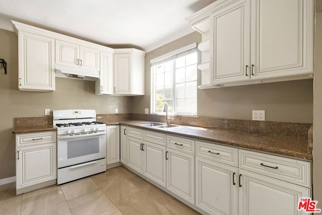 kitchen with white cabinets, white gas range, sink, and light tile patterned floors