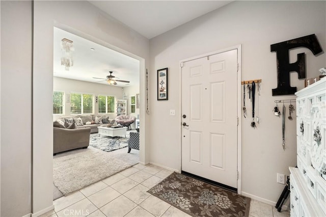foyer with a ceiling fan, light tile patterned floors, and baseboards