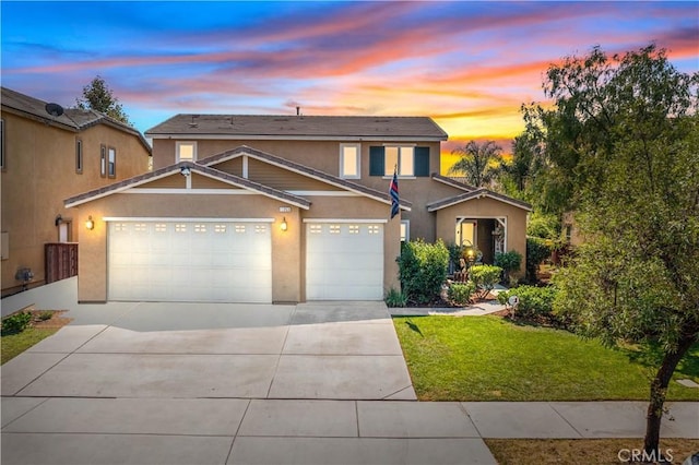 traditional home with a garage, a yard, concrete driveway, and stucco siding