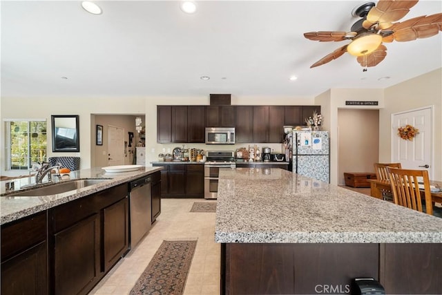 kitchen with dark brown cabinetry, a sink, a center island, stainless steel appliances, and recessed lighting