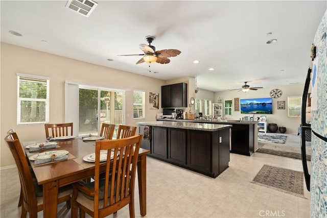 kitchen featuring stone countertops, ceiling fan, dark brown cabinets, a kitchen island, and kitchen peninsula