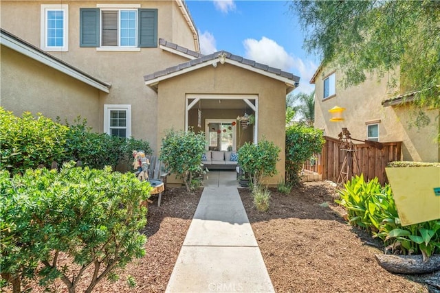property entrance featuring stucco siding and fence