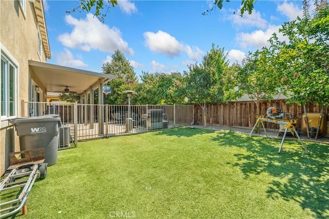 view of yard featuring a fenced backyard, a ceiling fan, and cooling unit