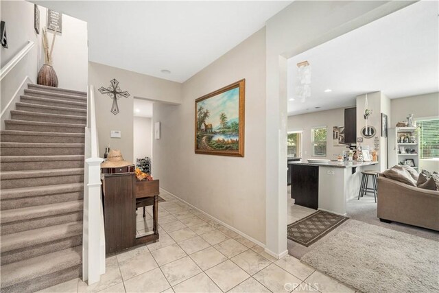 hallway with light tile patterned flooring, baseboards, stairway, and plenty of natural light