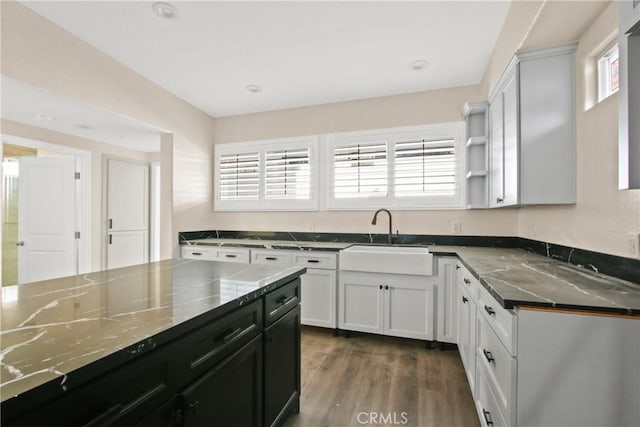 kitchen featuring white cabinetry, sink, dark stone counters, and dark hardwood / wood-style floors