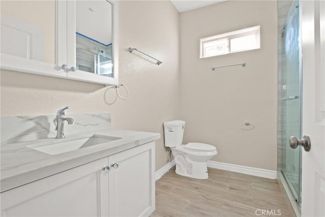 bathroom with vanity, toilet, and a shower with door