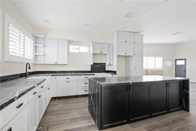 kitchen featuring a center island, white cabinetry, dark stone counters, and sink