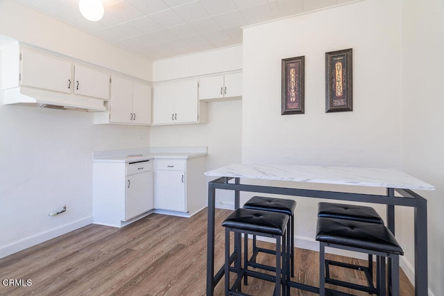 kitchen with white cabinetry, light hardwood / wood-style floors, and a breakfast bar area