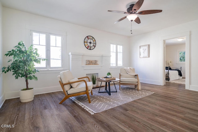 sitting room featuring ceiling fan, dark wood-type flooring, and a brick fireplace