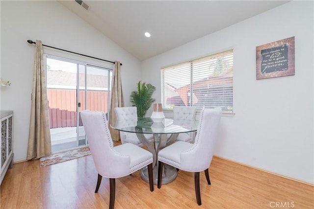 dining room featuring lofted ceiling, light wood-type flooring, and a healthy amount of sunlight