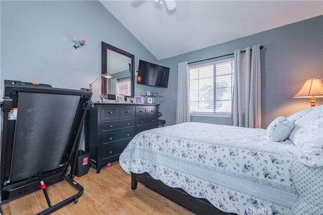 bedroom with ceiling fan, lofted ceiling, and light wood-type flooring