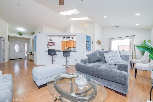 living room featuring light hardwood / wood-style floors and vaulted ceiling with skylight