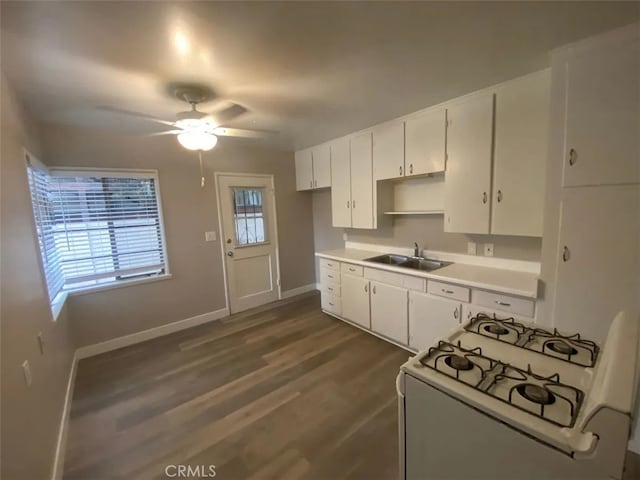 kitchen featuring dark hardwood / wood-style floors, white cabinetry, sink, and gas range gas stove