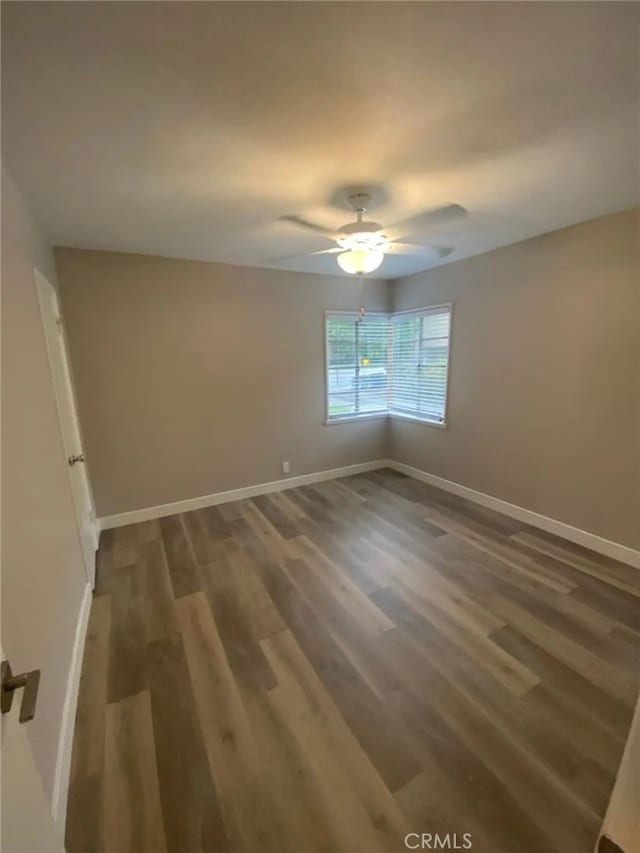 spare room featuring ceiling fan and dark wood-type flooring