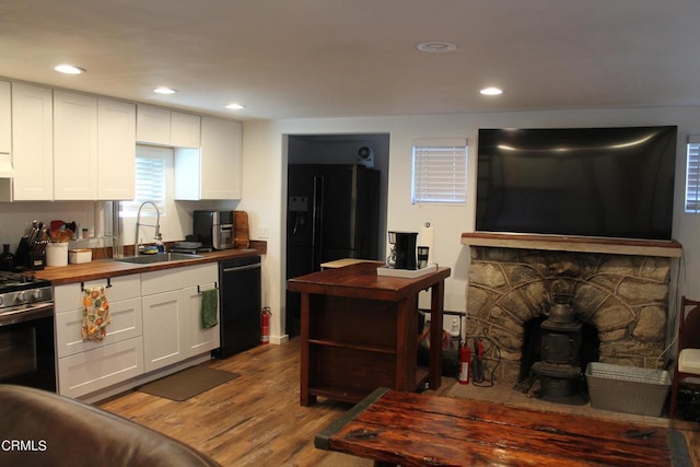 kitchen with white cabinetry, hardwood / wood-style floors, wooden counters, sink, and black appliances