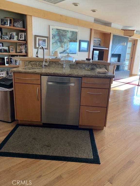 kitchen with dishwasher, light wood-type flooring, sink, and dark stone counters